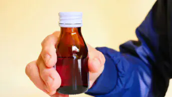 A man holds a bottle of medicine