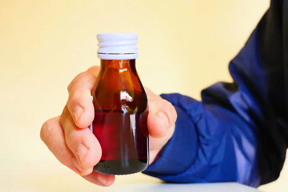 A man holds a bottle of medicine