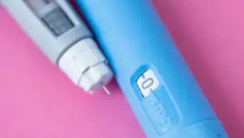 GLP-1 pen on a pink surface