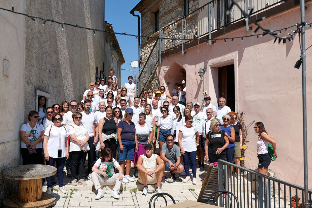 Mid-walk break, people gather between houses for the photo