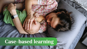Breastfeeding woman and baby lie on a blue/grey bed