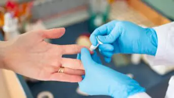 A healthcare professional pricks the finger of a patient