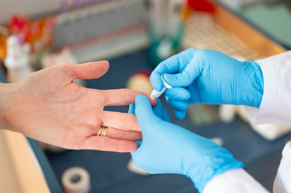 A healthcare professional pricks the finger of a patient