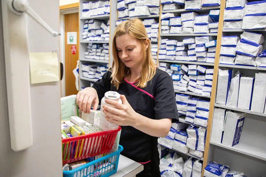 Trainee pharmacist in dispensary organising prescriptions
