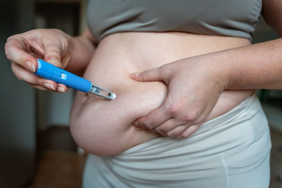 A woman uses a weight-loss injection on her stomach
