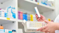 A pharmacist stocks a shelf at a pharmacy