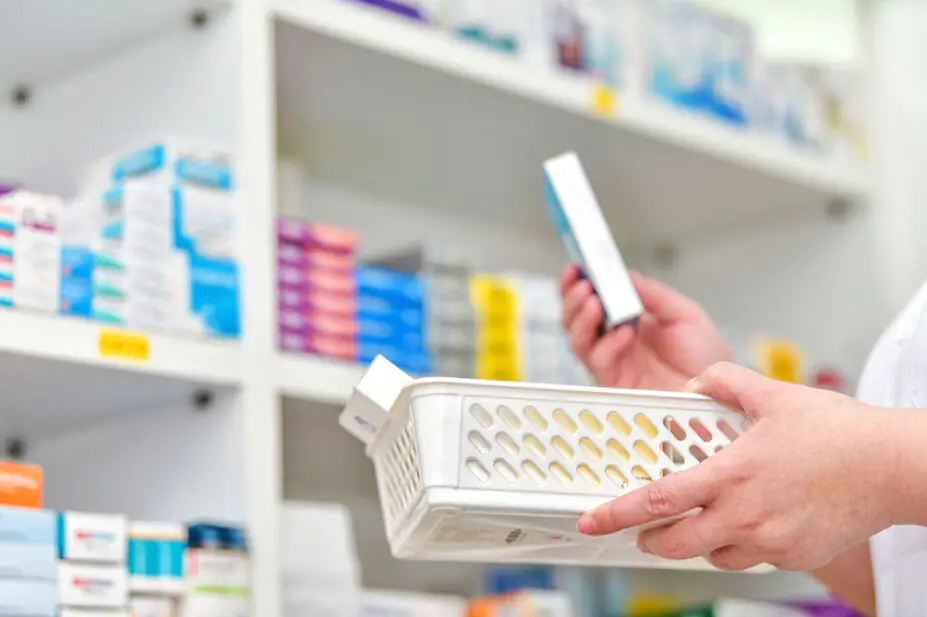 A pharmacist stocks a shelf at a pharmacy