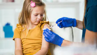 A young girl receives a vaccination from a healthcare professional