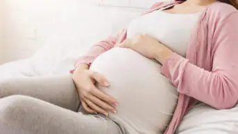 A pregnant woman holds her stomach