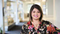 Amandeep smiles at the camera, wearing a floral shirt
