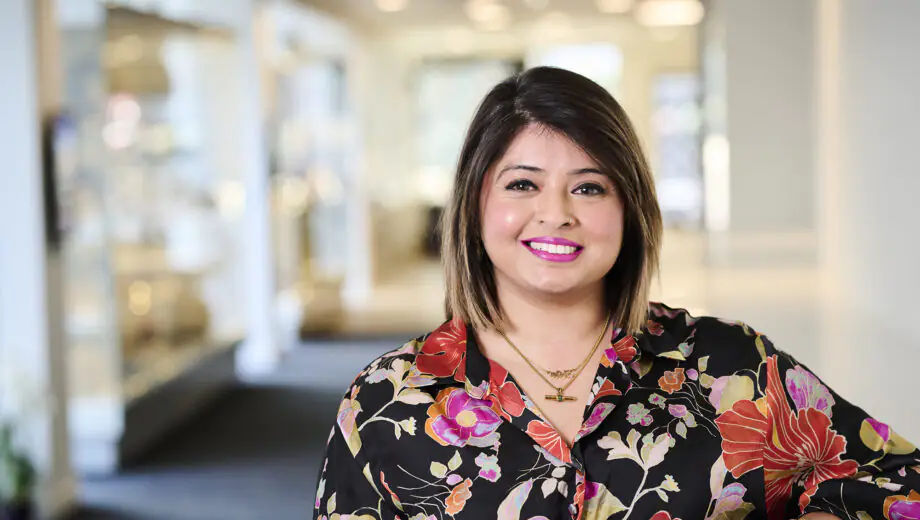 Amandeep smiles at the camera, wearing a floral shirt