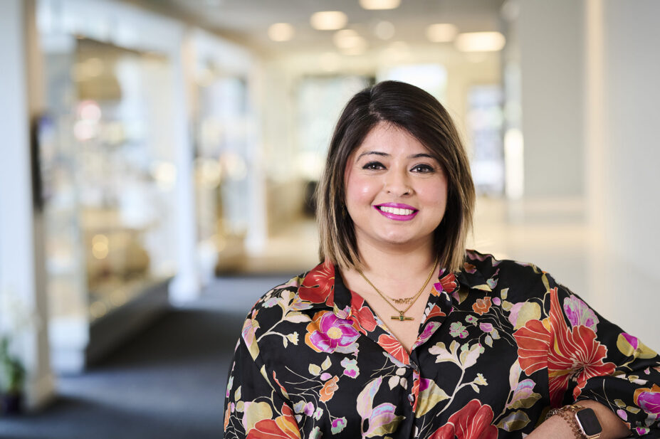 Amandeep smiles at the camera, wearing a floral shirt