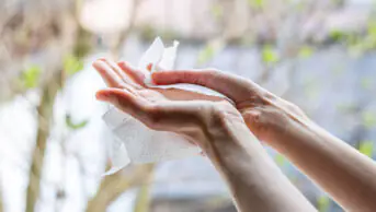 A woman uses an alcohol wipe on her hands