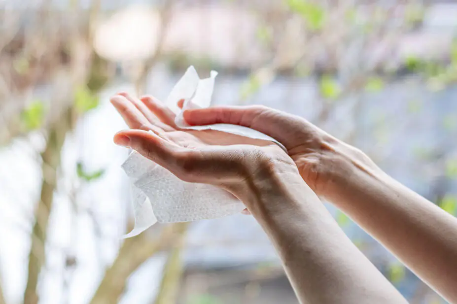 A woman uses an alcohol wipe on her hands