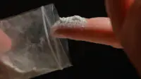 A person touches a bag of ketamine with their finger
