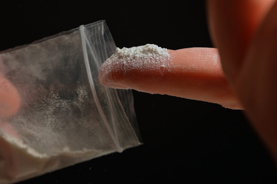 A person touches a bag of ketamine with their finger