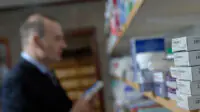 A pharmacist in the dispensary looking at medicine shelves