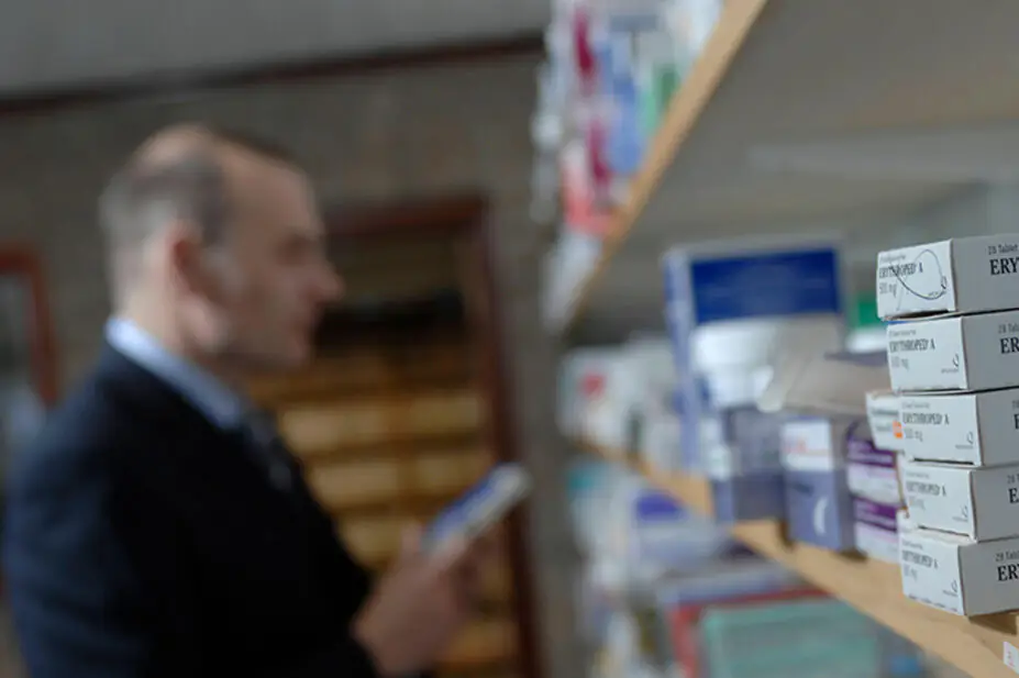A pharmacist in the dispensary looking at medicine shelves