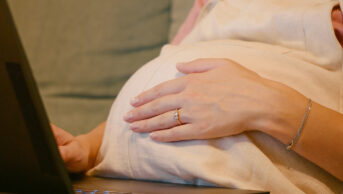 Pregnant woman on her laptop, on a sofa