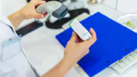 Pharmacist scanning a medicine box behind the counter