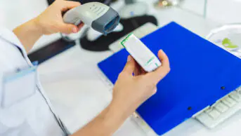 Pharmacist scanning a medicine box behind the counter
