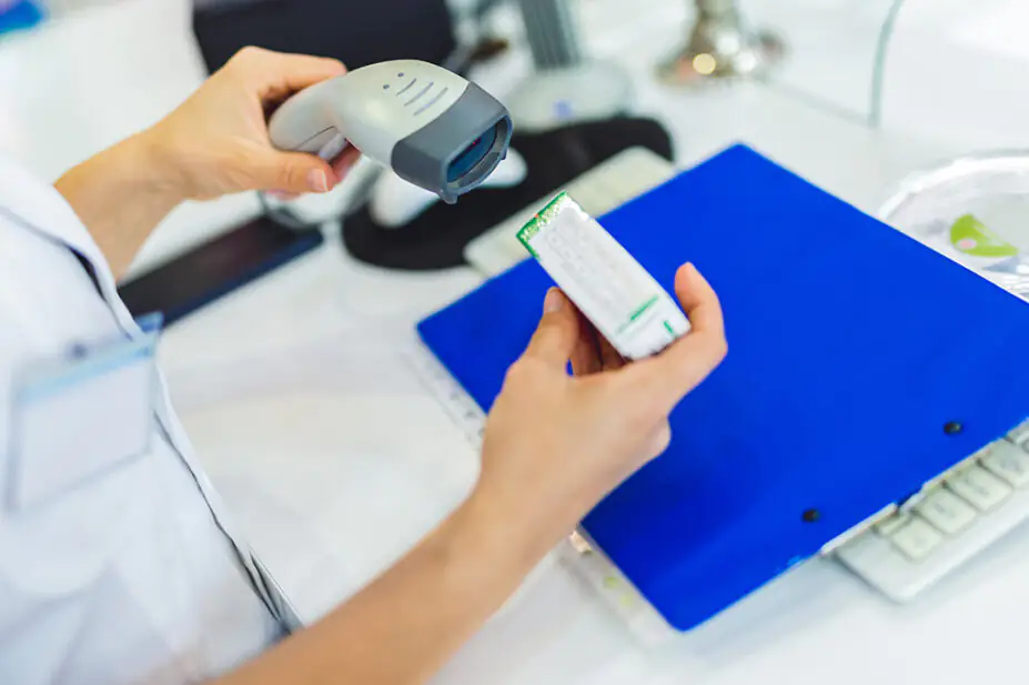 Pharmacist scanning a medicine box behind the counter