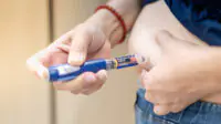A person injects themselves in the stomach with an insulin pen