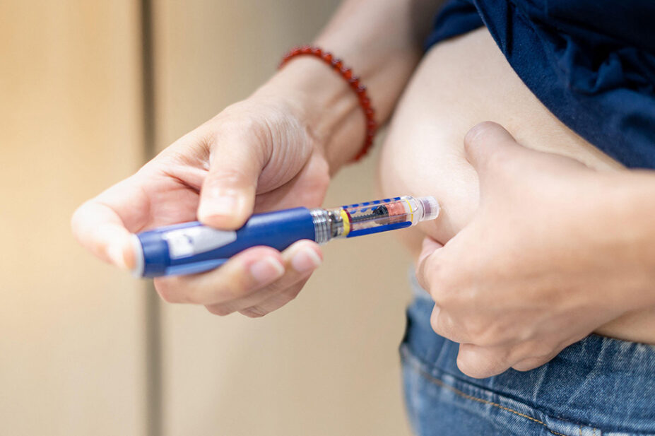 A person injects themselves in the stomach with an insulin pen