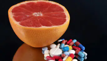Half grapefruit with a mixture of drugs close-up on black background