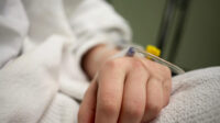 A close-up of a patient's hand with an IV