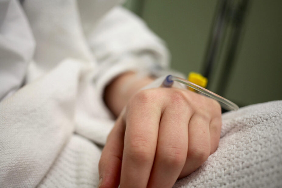 A close-up of a patient's hand with an IV
