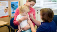 A child is held by her mother as she receives a vaccination