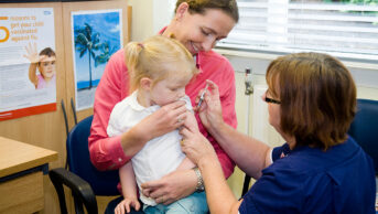 A child is held by her mother as she receives a vaccination