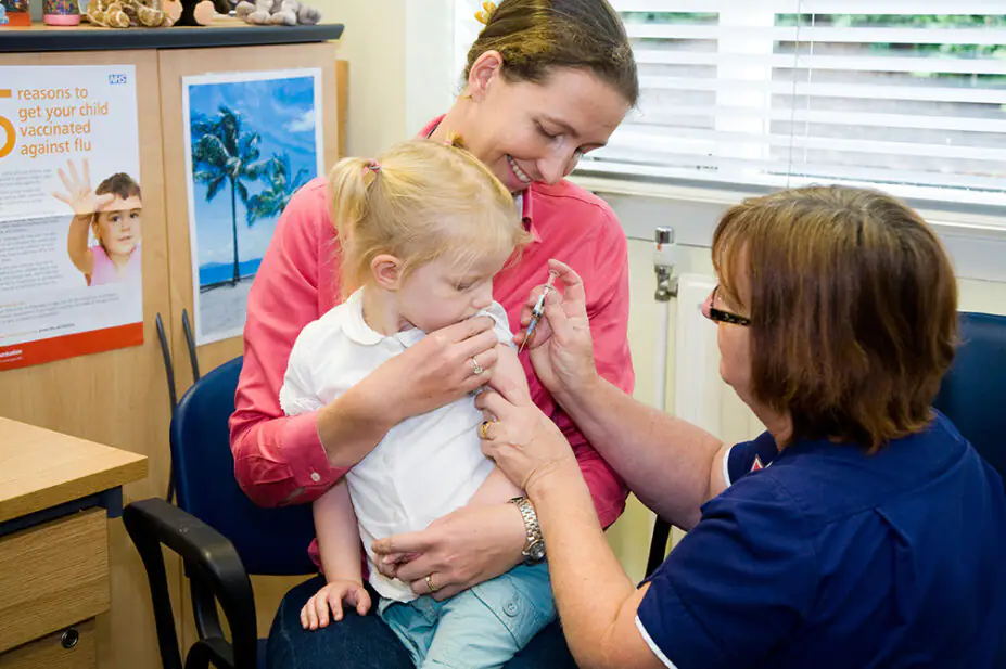 A child is held by her mother as she receives a vaccination