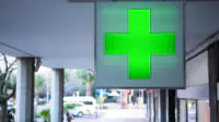 The green cross sign outside of a community pharmacy