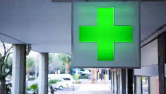 The green cross sign outside of a community pharmacy