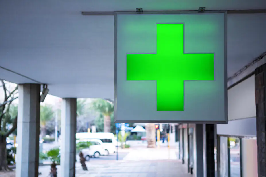The green cross sign outside of a community pharmacy