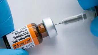A healthcare professional fills a syringe with naloxone