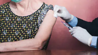 Older woman receiving vaccinations in upper arm