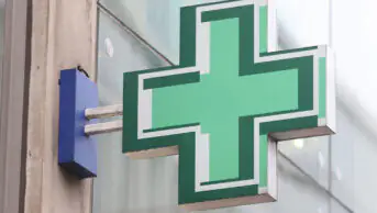 The green sign outside of a community pharmacy