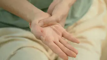 woman holding hands, suggestive of pain