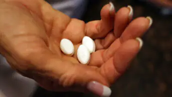 A woman holds three gabapentinoid tablets in her hand