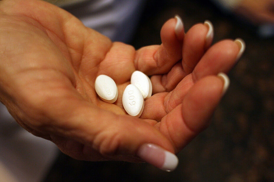 A woman holds three gabapentinoid tablets in her hand