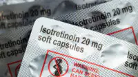 Packs of isotretinoin 20mg soft capsules with warning label in red and an image of pregnant women with a red line across it