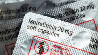 Packs of isotretinoin 20mg soft capsules with warning label in red and an image of pregnant women with a red line across it