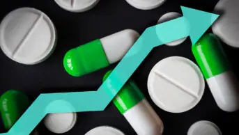 Black background with white pills and green and white tablets and a blue arrow pointing upwards