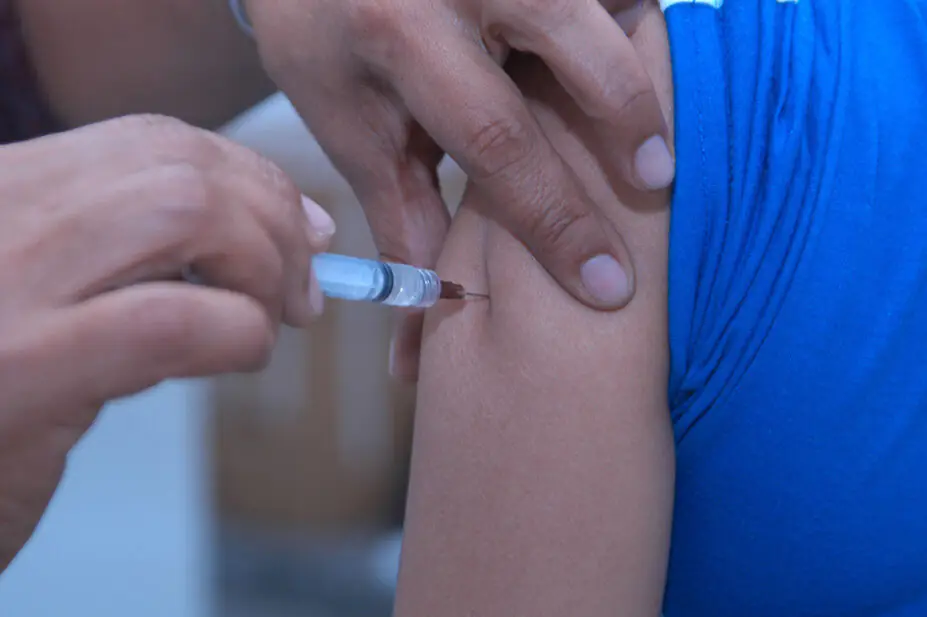 A healthcare professional gives a patient and injection in their arm