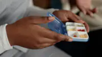 Close up of hands of holding small pill case organiser with medication
