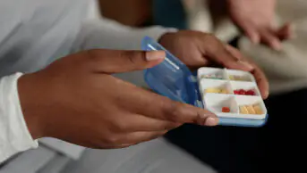 Close up of hands of holding small pill case organiser with medication