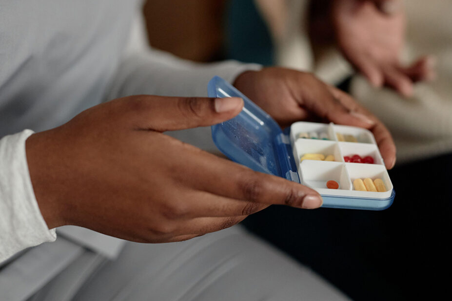 Close up of hands of holding small pill case organiser with medication